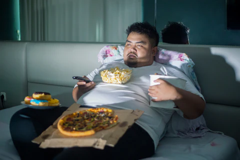 orang gemuk tengah makan atas sofa